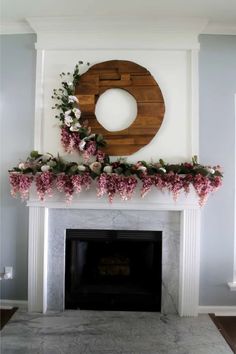 a fireplace decorated with flowers and greenery in front of a wreath on the mantle