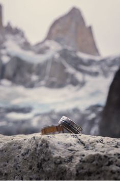 a pair of flip flops sitting on top of a rock in front of snow covered mountains