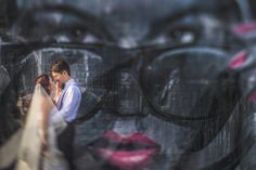 a man and woman standing next to each other in front of a graffiti covered wall