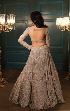 This metallic nude grey lehenga features all-over sequin, crystal, pearls, and cutdana embroidery. Paired with a corseted full sleeves blouse and an embroidered dupatta in net.DELIVERY TIMEPlease allow 8-12 weeks for your outfit to arrive.FABRIC DETAILSNetProfessional cleaning only. Lehenga Blouse Designs For Wedding, Full Sleeve Golden Blouse Designs, Lehenga Blouse Back Neck Designs Latest, Back Design For Lehenga Blouse, Lehenga Back Neck Design, Stylish Blouse Design Latest For Lehnga, Full Sleeves Blouse Design For Lengha, Lengha Blouse Designs Back, Lengha Blouse Designs Full Sleeves