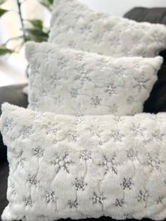 two white pillows sitting on top of a couch next to a black pillow case with snow flakes