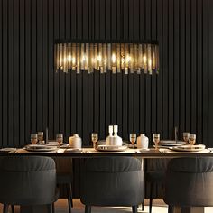 a dining room table set with plates, glasses and wine bottles on it in front of a black wall