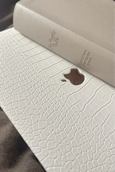 an apple logo is on the back of a white leather case