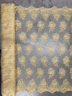 a gold and grey fabric with flowers on it, next to a piece of cloth that has been cut in half