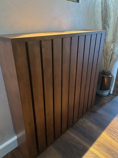 a wooden radiator sitting on top of a hard wood floor next to a plant