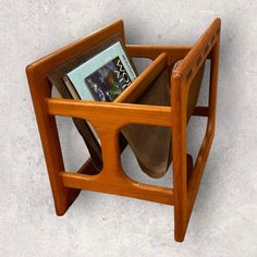 a wooden chair with a magazine holder on it's back and two books in the seat