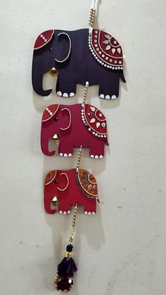 three elephants are hanging on the wall with beads and chains attached to it's backs