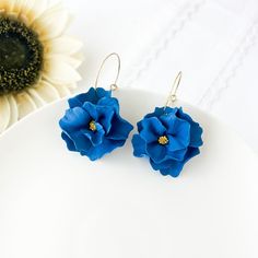 Elevate your style with our stunning Indigo Blue Earrings for women, perfect for adding a touch of elegance to any outfit. These Navy Blue Bridesmaid Earrings with a hint of gold are ideal for weddings or special occasions. Handcrafted with botanical-inspired designs, these dangle earrings feature delicate flowers sculpted from lightweight polymer clay, making them comfortable to wear all day long. Whether you're a plant mom or looking for a thoughtful gift, these hypoallergenic earrings with surgical steel hoops are ideal for sensitive ears. For extra versatility, there's a clip-on option available too. Shop now and treat yourself or a loved one to these unique and stylish botanical jewelry earrings. Since all items are handmade you may see slight variations in color or pattern from the p Blue Flower Hoop Earrings Gift, Blue Flower Hoop Earrings As Gift, Blue Flower-shaped Hoop Earrings, Blue Flower Shaped Hoop Earrings, Blue Handmade Flower Drop Earrings, Blue Dangle Flower Earrings For Wedding, Polymer Clay Flower Drop Earrings For Wedding, Blue Clip-on Earrings For Wedding, Blue Elegant Earrings With 3d Flowers