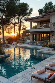 an outdoor swimming pool with chaise lounges next to it and the sun setting in the background