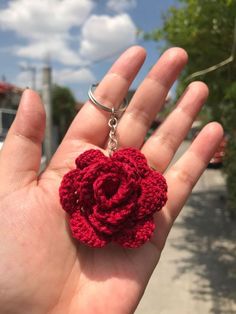 a crocheted rose keychain is shown in the palm of someone's hand