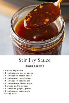 a spoon full of stir fry sauce sitting on top of a jar filled with liquid