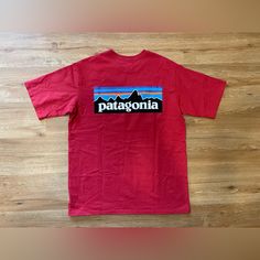 Add Some Eco-Friendly Style To Your Wardrobe With This Patagonia Men's P-6 Logo Responsibili-Tee T-Shirt In Sumac Red. The Short-Sleeved Tee Features A Solid Pattern With A Crew Neck And A Regular Fit, Making It A Comfortable Option For Everyday Wear. The Shirt Is Made From High-Quality Materials With Double-Sided Features And Accents, Including The Iconic Patagonia Logo. This Red Tee Is Perfect For Men Who Want To Show Off Their Love For The Outdoors While Maintaining A Stylish And Eco-Friendly Look. It's Available In Size Small And Is Sure To Become A Staple In Any Wardrobe. Sporty Red Tops For Outdoor Activities, Red Short Sleeve T-shirt For Outdoor, Red Short Sleeve Tops For Outdoor, Red Cotton Tops For Outdoor Activities, Casual Short Sleeve Patagonia Top, Patagonia Relaxed Fit Crew Neck T-shirt, Casual Patagonia Tops With Graphic Print, Casual Patagonia Cotton T-shirt, Red Tops With Graphic Print For Outdoor