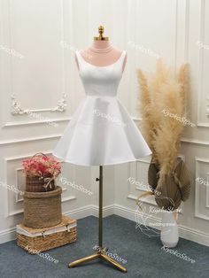 a white dress is on display in front of a vase with flowers and a feather