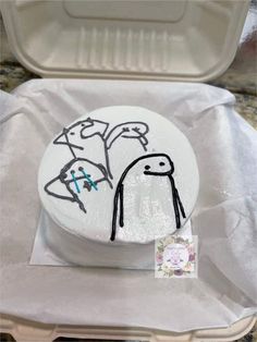 a white cake in a plastic container with some writing on it and an image of two people