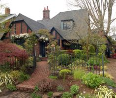 a house with lots of flowers and plants around it