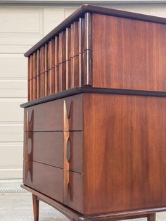 a large wooden cabinet sitting on top of a cement floor next to a garage door