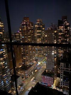 the city is lit up at night from an apartment window