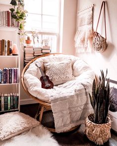 a room with a chair, bookshelf and guitar on the floor in it