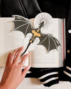 a person is holding an open book with a bat cut out on it