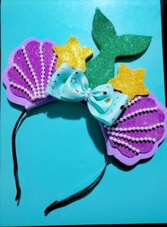 there is a purple and green hair bow with stars on the top, and a mermaid tail