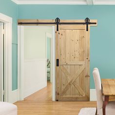 a dining room with a wooden table and white chairs next to a sliding barn door