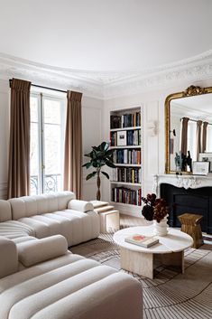 a living room filled with furniture and a fire place in front of a mirror on the wall