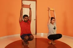 two people sitting on the floor with their hands in the air while doing yoga exercises