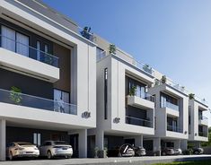 several cars parked in front of two large white buildings with balconies on the second floor