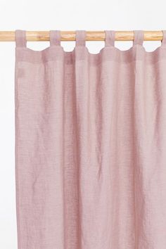 a pink curtain hanging on a wooden rod