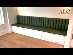 a green bench sitting on top of a hard wood floor next to a white wall