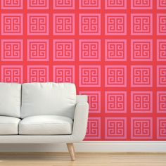 a white couch sitting in front of a red wall with an intricate design on it