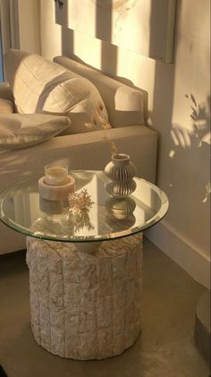 a glass table sitting in front of a couch next to a window with sunlight streaming through it