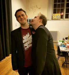 two men standing next to each other on a wooden floor