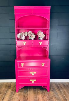 a pink china cabinet with flowers on top