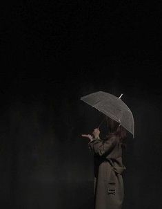 a woman standing in the dark holding an umbrella over her head and pointing at something