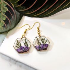 a pair of earrings with purple flowers on them