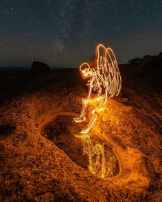 a light painting angel sitting on top of a hill