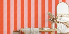 a bedroom with an orange and pink striped wallpaper, a white bed and mirror