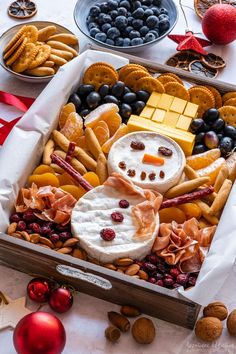 a box filled with cheese, crackers, fruit and other food items on top of a table