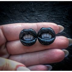 a pair of black earrings with an open mouth in the palm of someone's hand