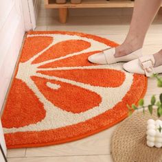 a woman standing on top of an orange and white rug next to a potted plant