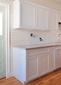 a kitchen with white cabinets and wood floors