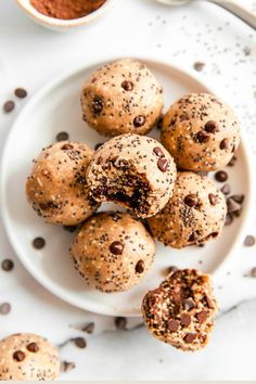 chocolate chip muffins on a white plate next to a cup of cocoa powder