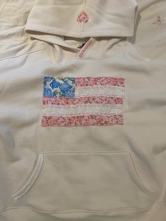 a white hoodie with an american flag patch on the front and pink flowers on the back