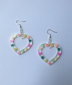 a pair of heart shaped earrings with multicolored polka dots on the outside and inside