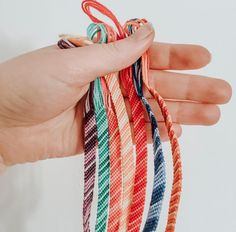 a hand holding several different colored bracelets