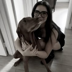 a woman in glasses hugging a dog on the floor