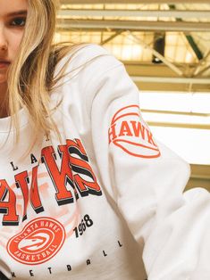 a woman in a white sweatshirt holding a skateboard