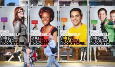 two people walking past a book store with posters on the front windows and behind them