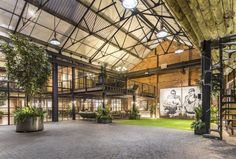 the inside of an industrial building with lots of windows and plants in pots on the floor